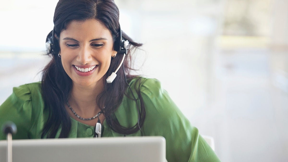 Smiling woman using laptop with headset on