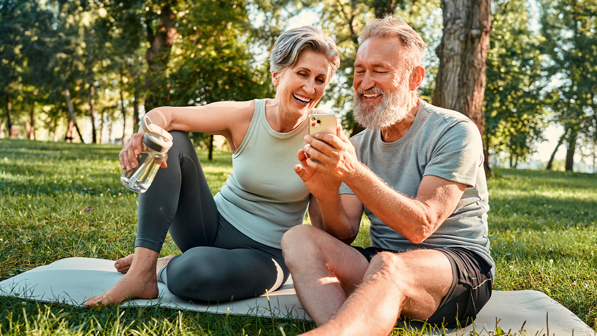 Older couple outdoors in park connected to Wi-FI and on phone