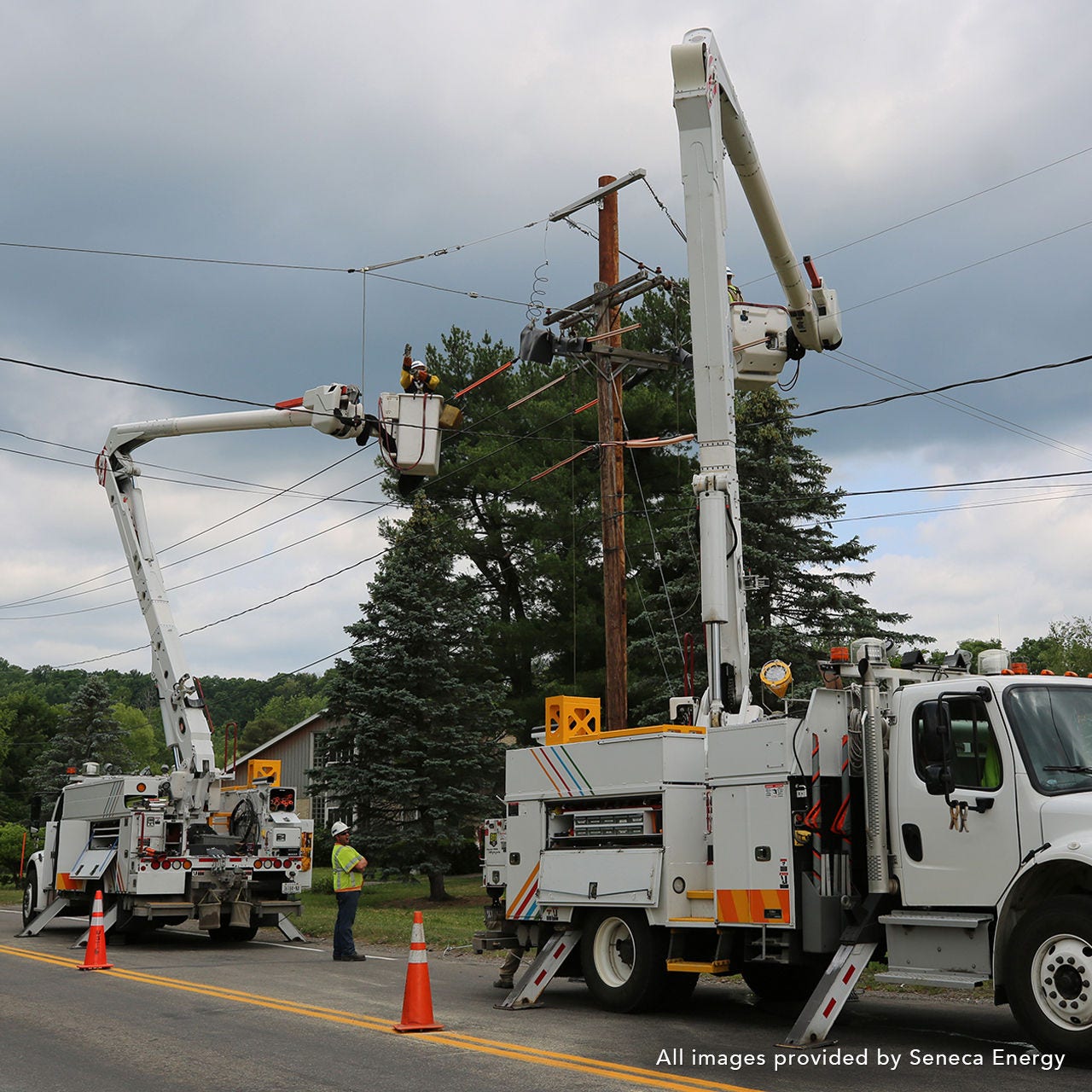 Two large work trucks with workers in each man lifter working on a power line