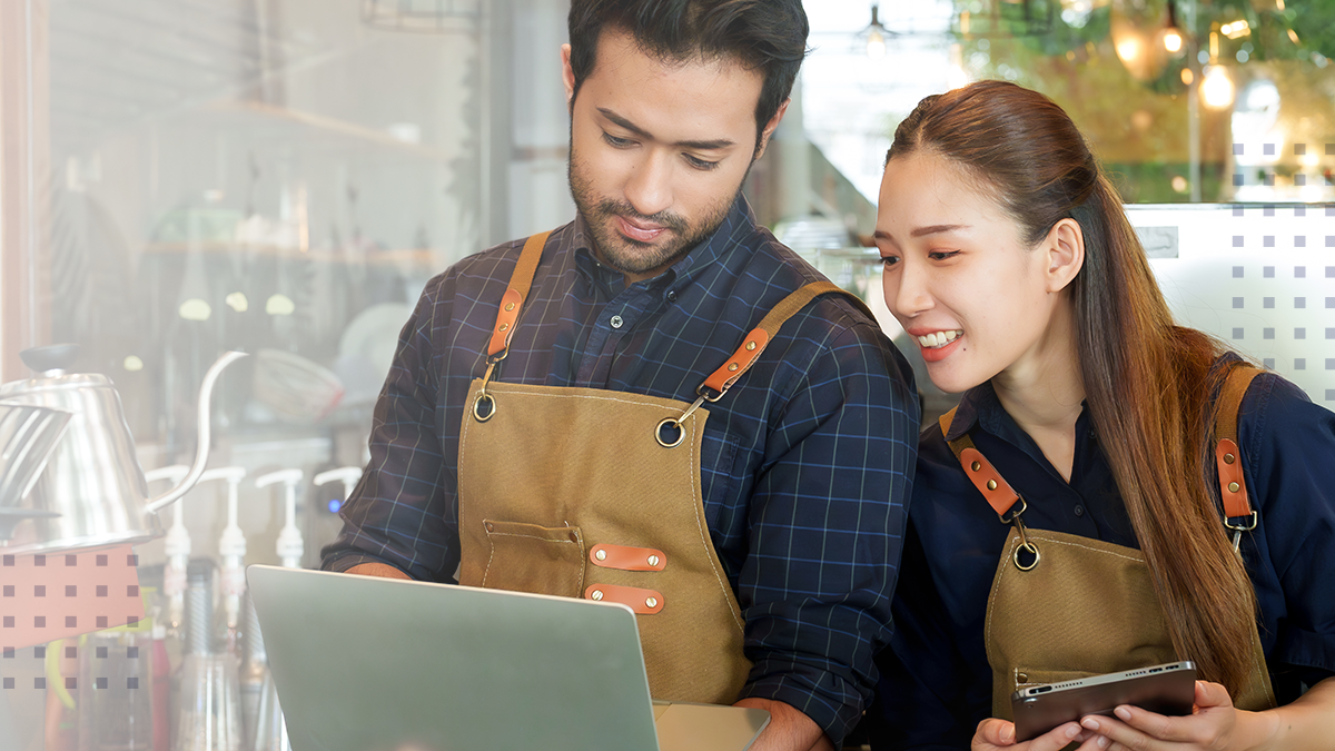 man and woman employees at coffee shop working on devices