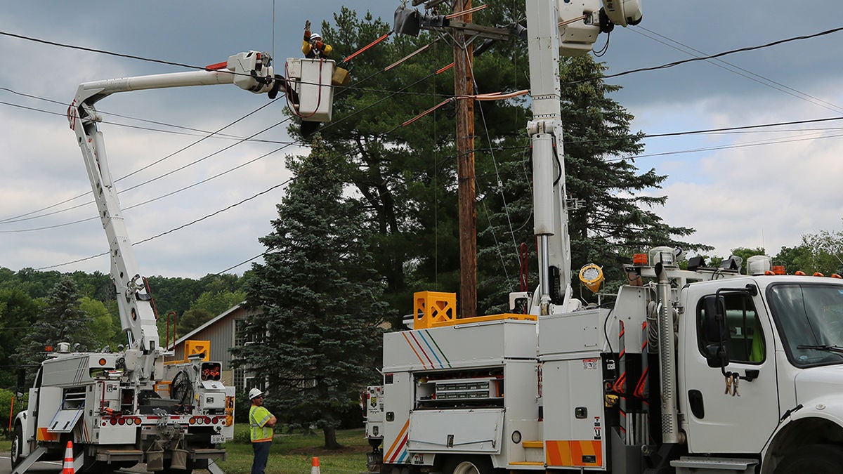 Two large work trucks with workers in each man lifter working on a power line