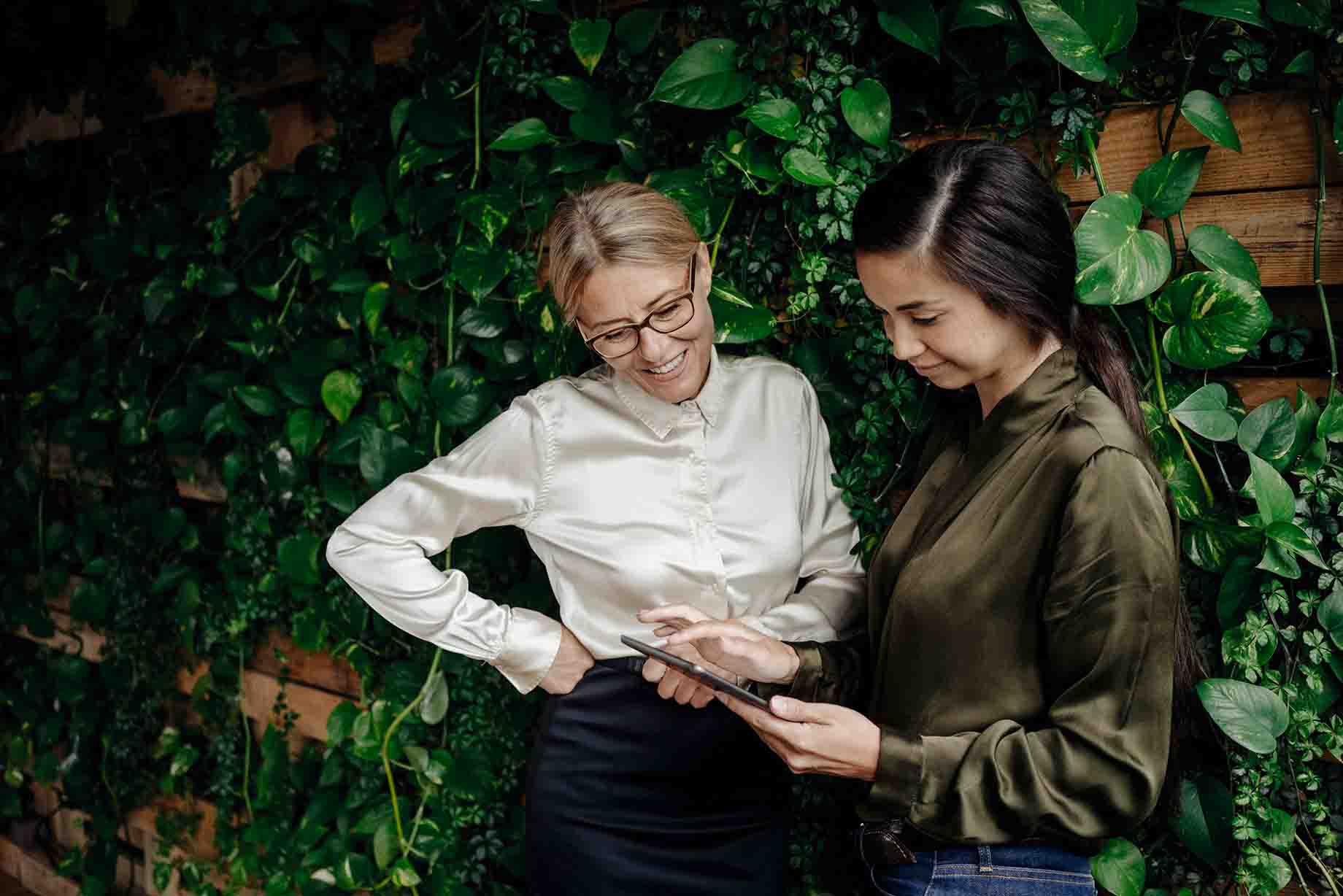 two women outdoors with tablet