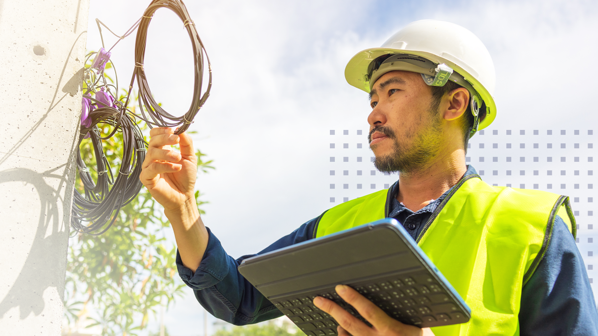 An electric coop employee wearing a vest and hardhat while inspecting wires