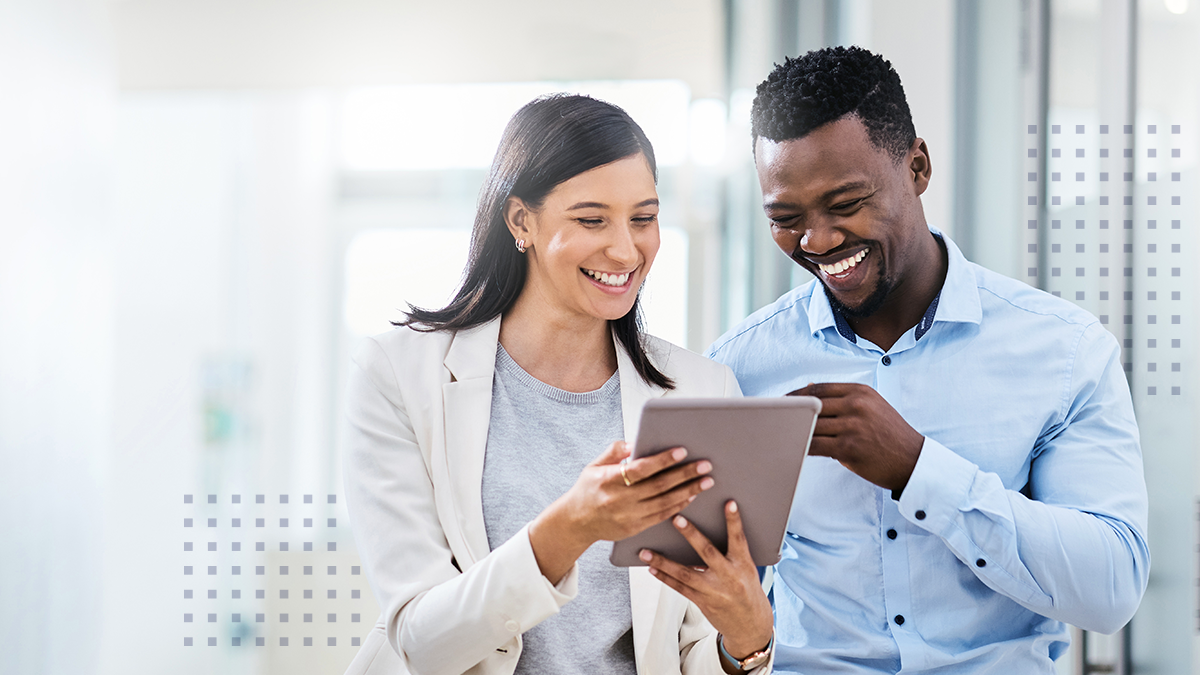 A man and woman smiling together while viewing a tablet