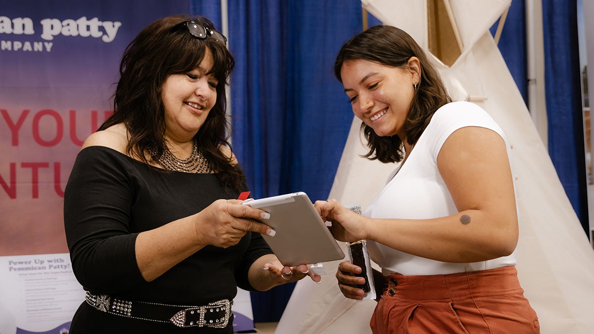 Two women using a tablet at a tribal broadband convention