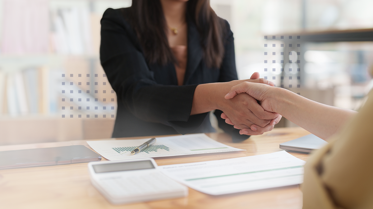 Business executives shaking hands at table in office