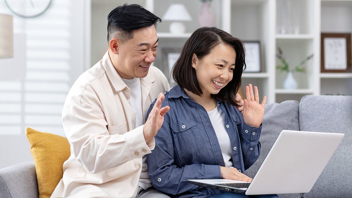 couple waving to laptop during video call