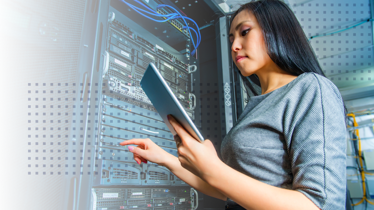 Woman working in a server room while looking at a tablet