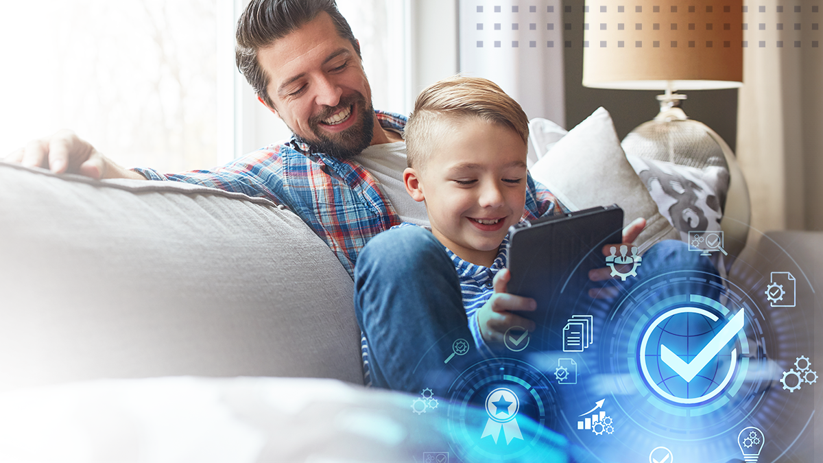 A smiling father with his son playing with a tablet on the couch