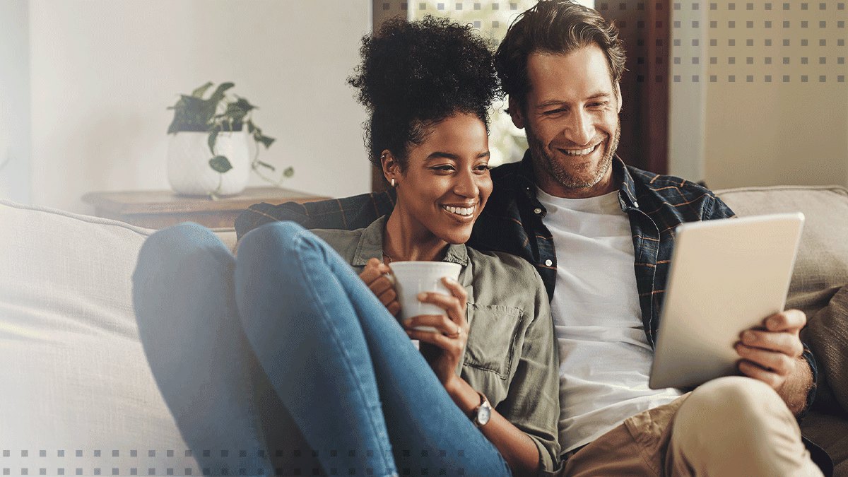 Closeup of smiling man and woman using digital tablet sitting on sofa in living room