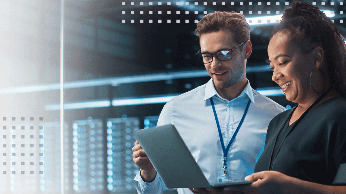 it technicians with a laptop computer are talking in data center while working next to server racks