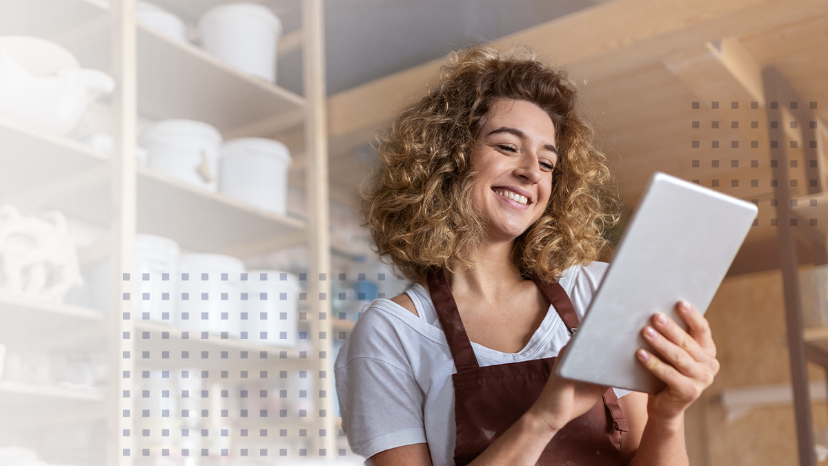 A woman smiling while using a tablet at a small business
