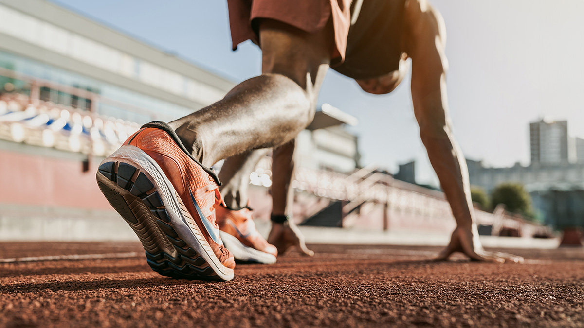 Close up of male athlete getting ready to start running on track