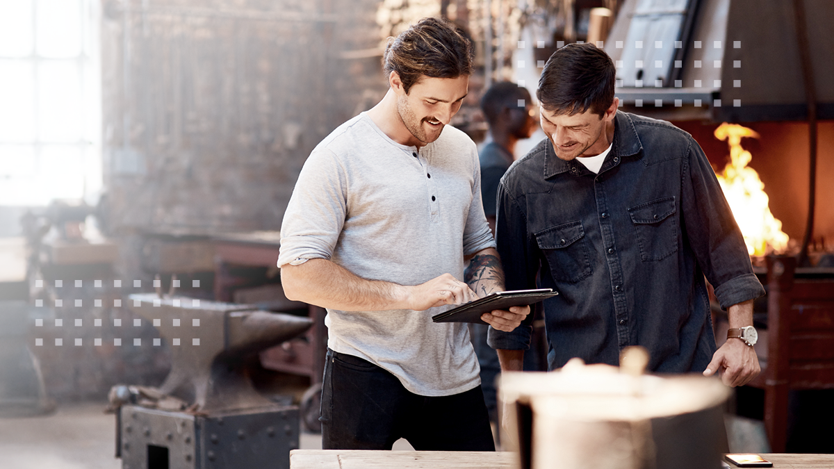 Cropped shot of two handsome young using a digital tablet while working together inside their workshop